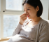 Pregnant woman pinching her nose, suffering congestion, considering nasal strips for relief.
