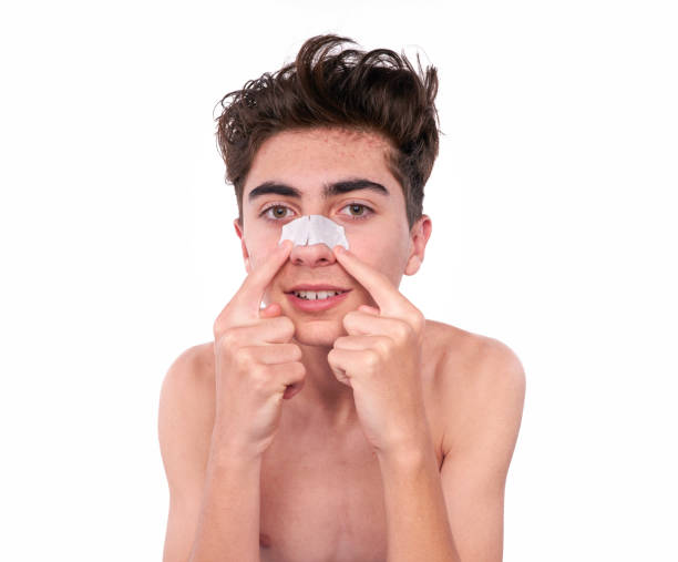 Young man applying nasal strips to clean his nose.