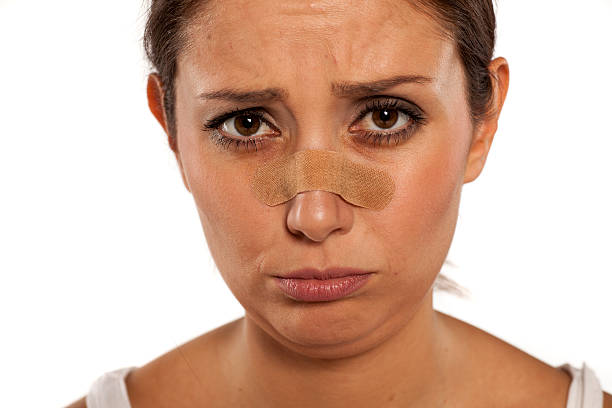 Upset woman with a beige adhesive nasal strips on her nose.