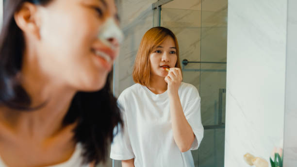 Woman wearing a nasal strips while her friend brushes teeth in the bathroom.