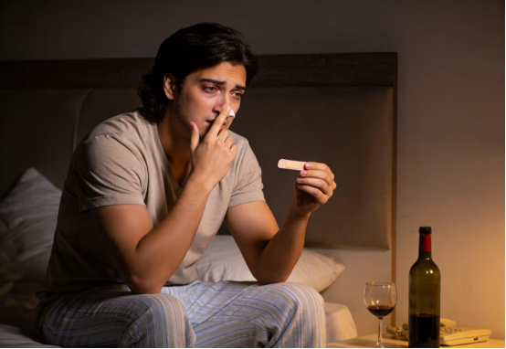 Man contemplating applying nasal strips in bed at night for clearer breathing.