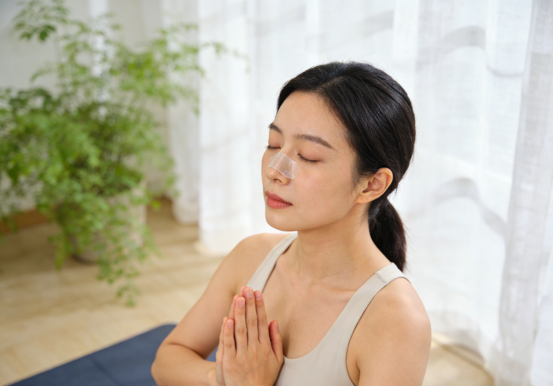 Calm woman with hands together, wearing nasal strips for clearer breathing during yoga.