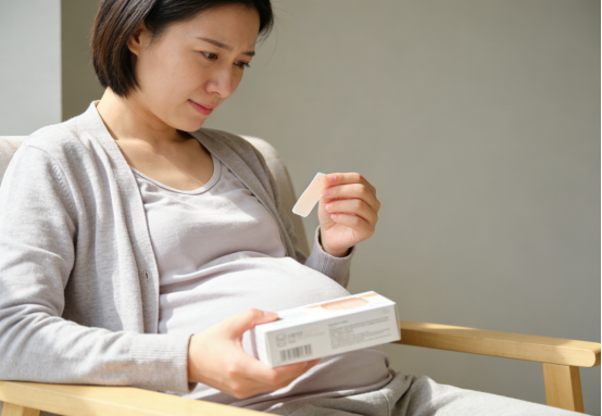 Pregnant woman examining a box of nasal strips for improved nasal breathing.