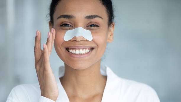 Happy young woman smiling, wearing a white nasal strip for clearer skin.