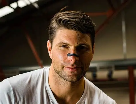 Smiling man confidently wearing a black nasal strip for better airflow.