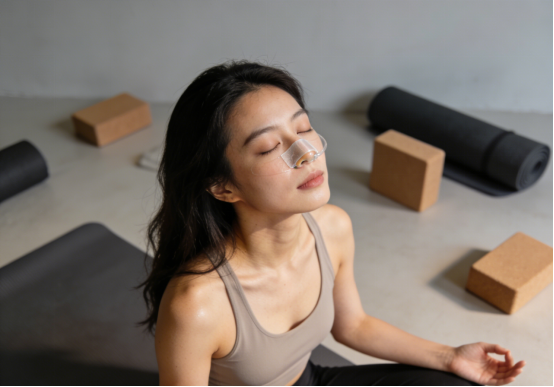 Woman meditating on yoga mat with nasal strips, promoting relaxed breathing during practice.