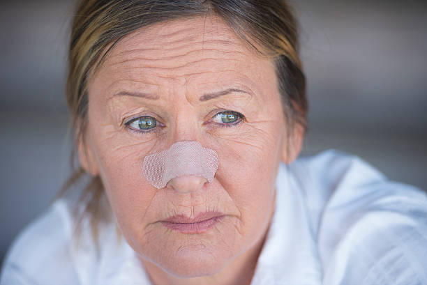 Mature woman wearing a textured, flesh-colored nasal strip on her nose.